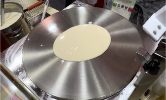 クレープ機械のステンレスプレート中心に生地を流し入れる工程